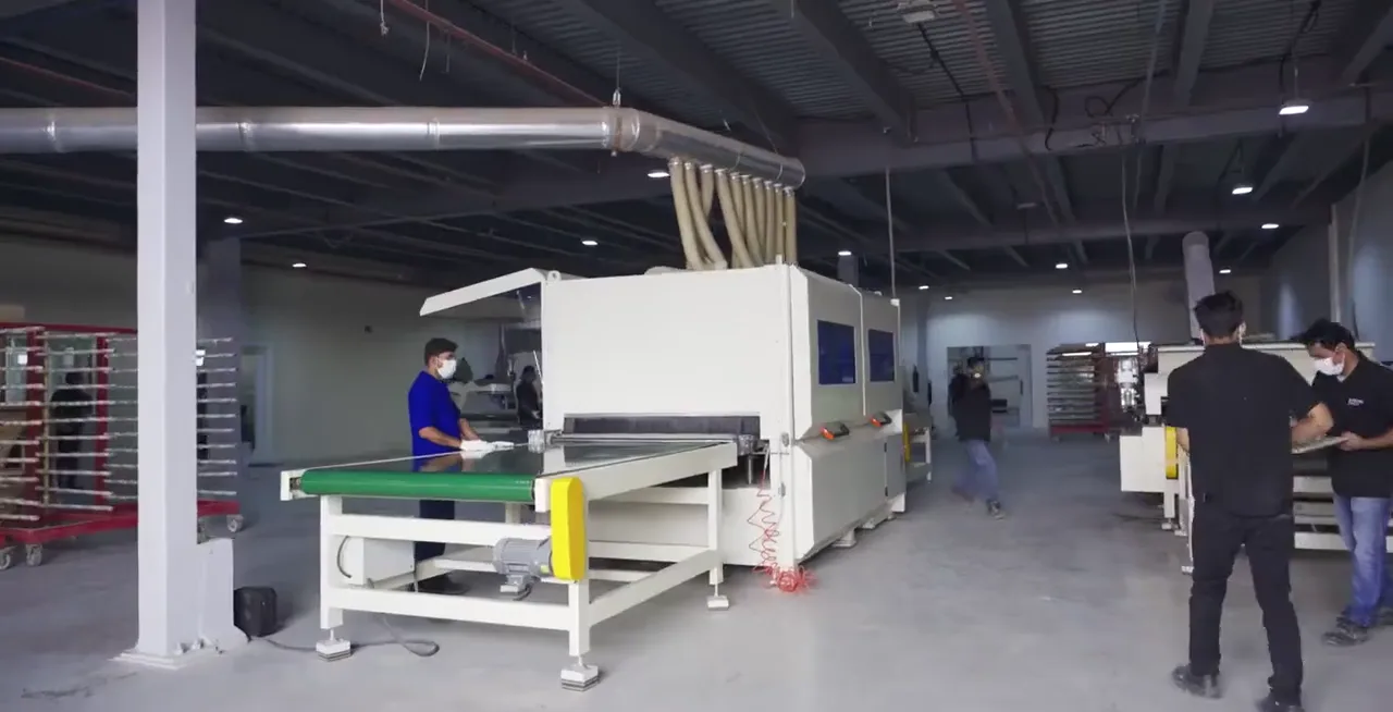 Panels passing through the edge-banding machine in the joinery hall